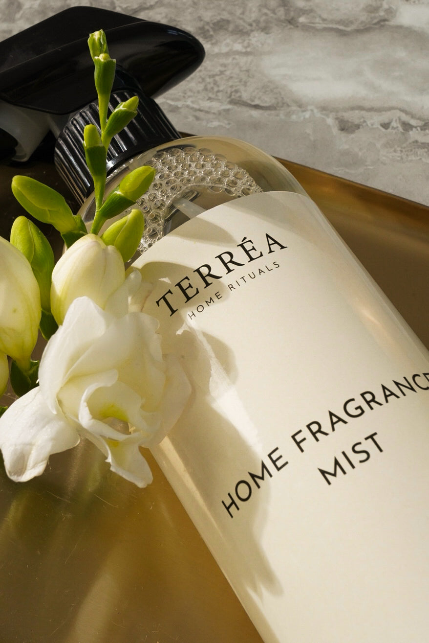 Terréa Home Fragrance Mist 500 ml close-up with white freesia on a warm-toned marble counter.