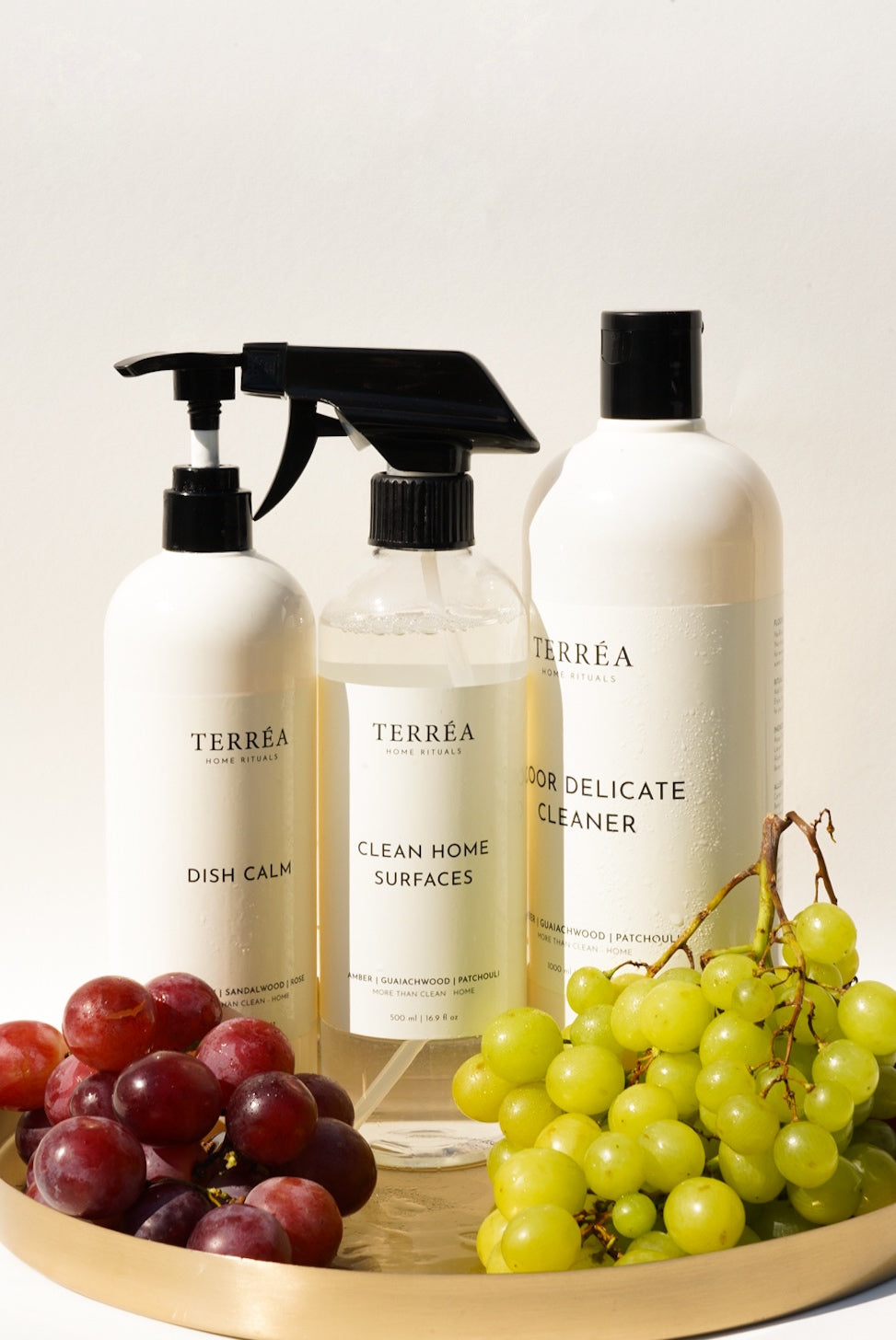 Terréa Dish Calm, Clean Home Surfaces and Floor Delicate Cleaner styled on a golden tray with red and green grapes in warm natural light.