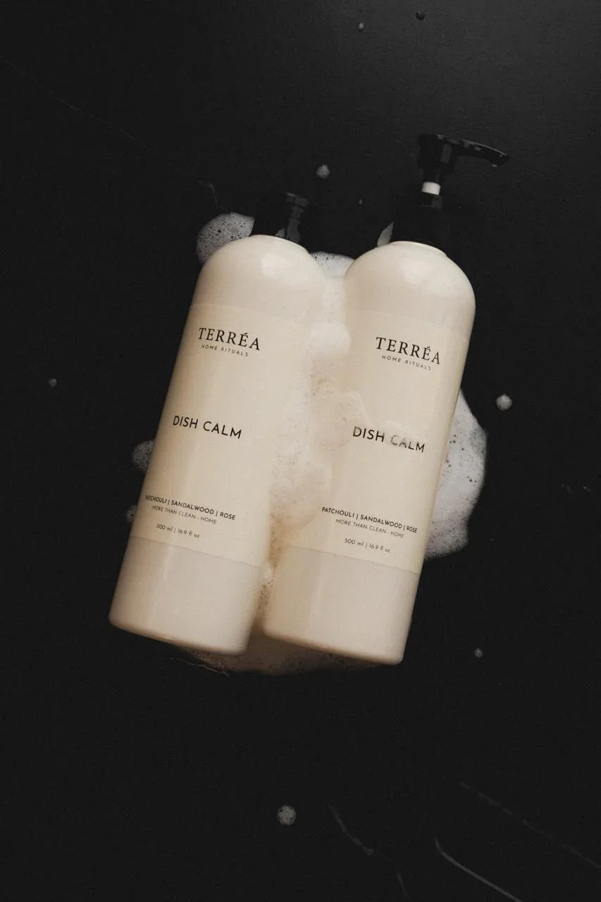 Two bottles of Terrea Dish Calm on a black background with soap bubbles.