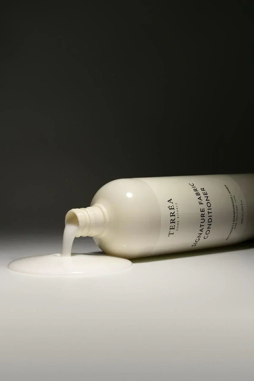 Ferrea fabric conditioner bottle with white liquid on a dark background