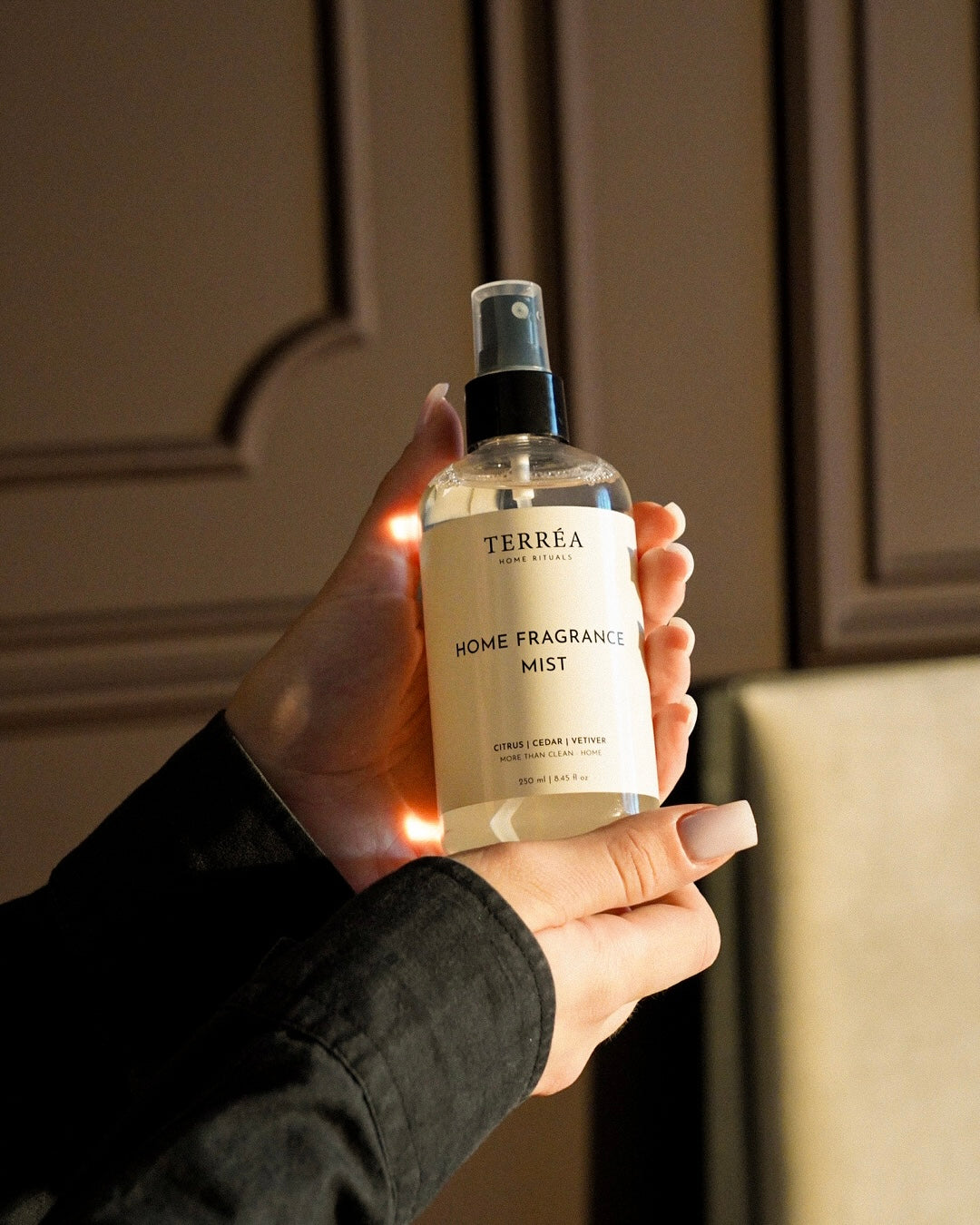 Terréa Home Fragrance Mist room and linen spray held against a panelled wall in the evening