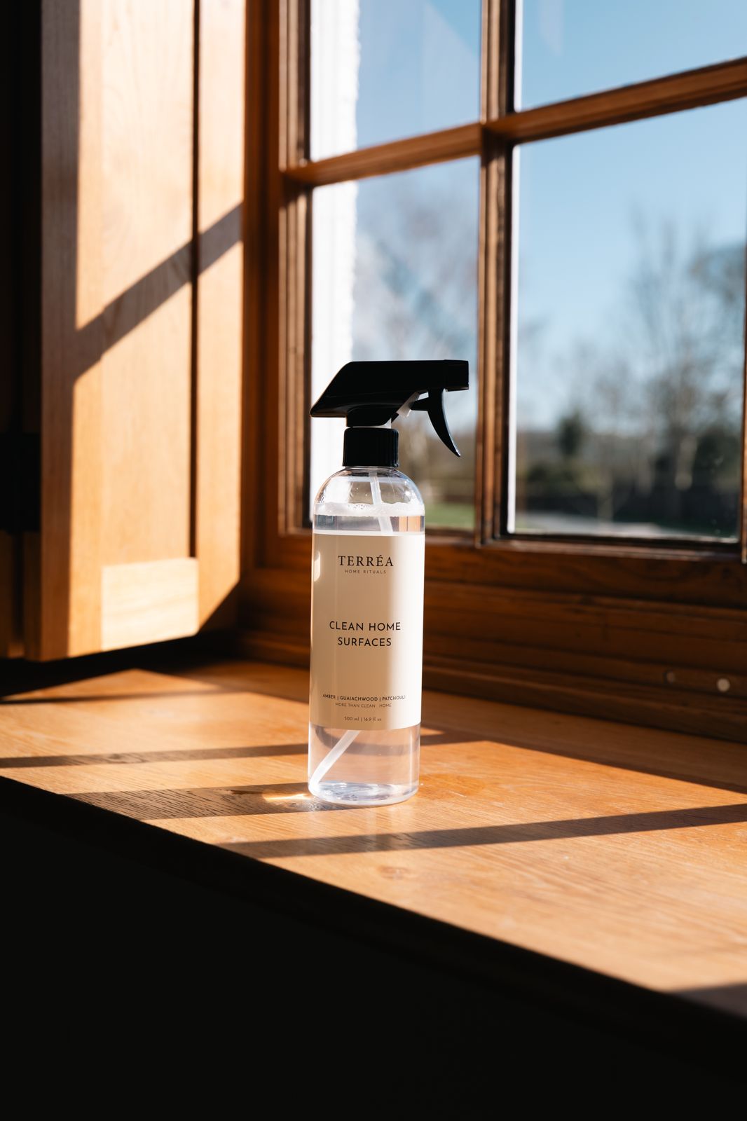 Eco-friendly home surface cleaner spray on wooden windowsill, natural light, sustainable luxury home care