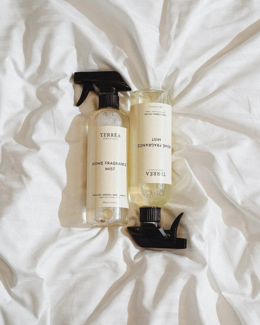 Home fragrance mist spray bottles on white linen, eco-friendly luxury home care