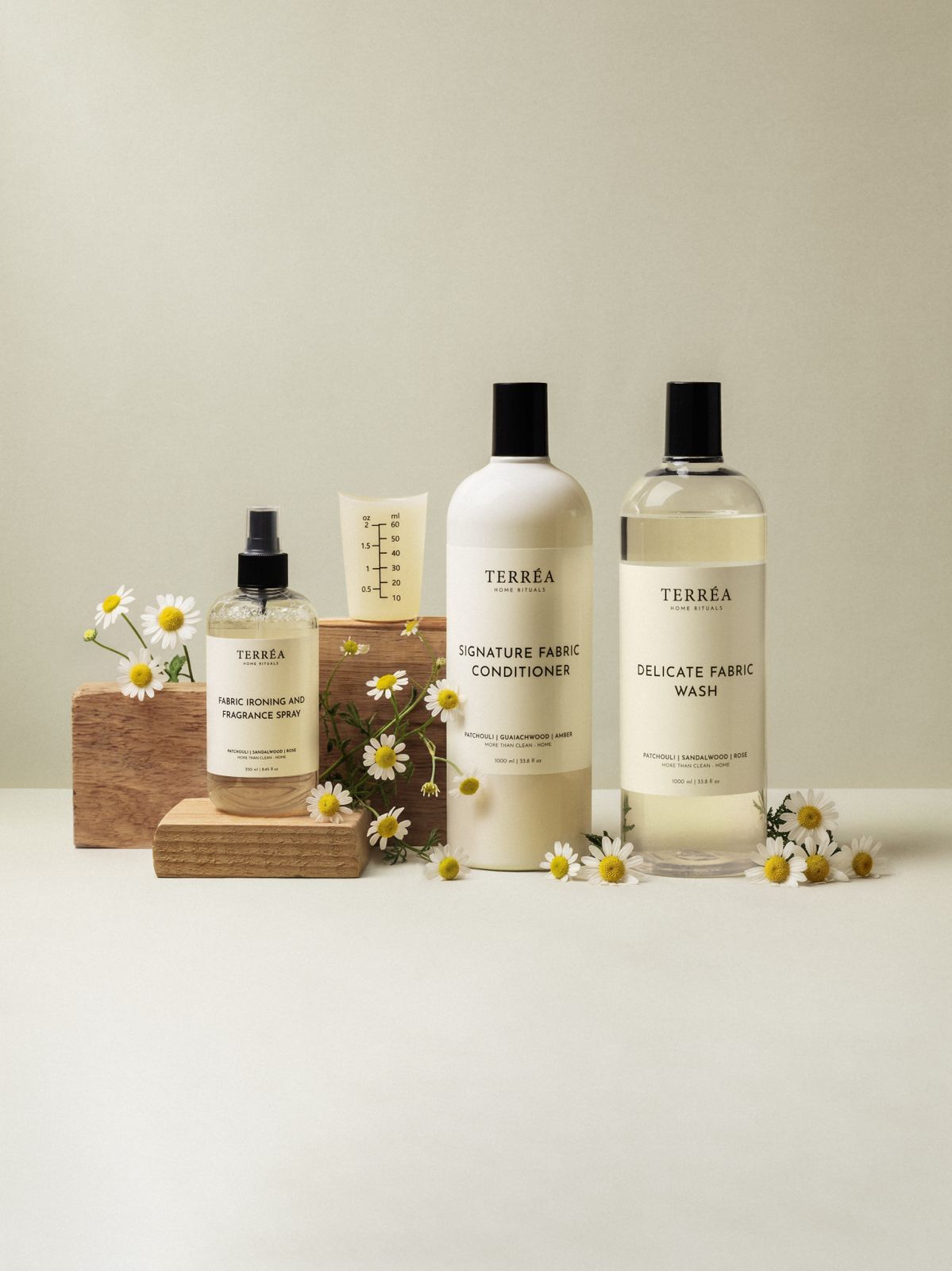 Eco-friendly fabric care set with fragrance spray, conditioner & wash, styled with daisies and wood blocks