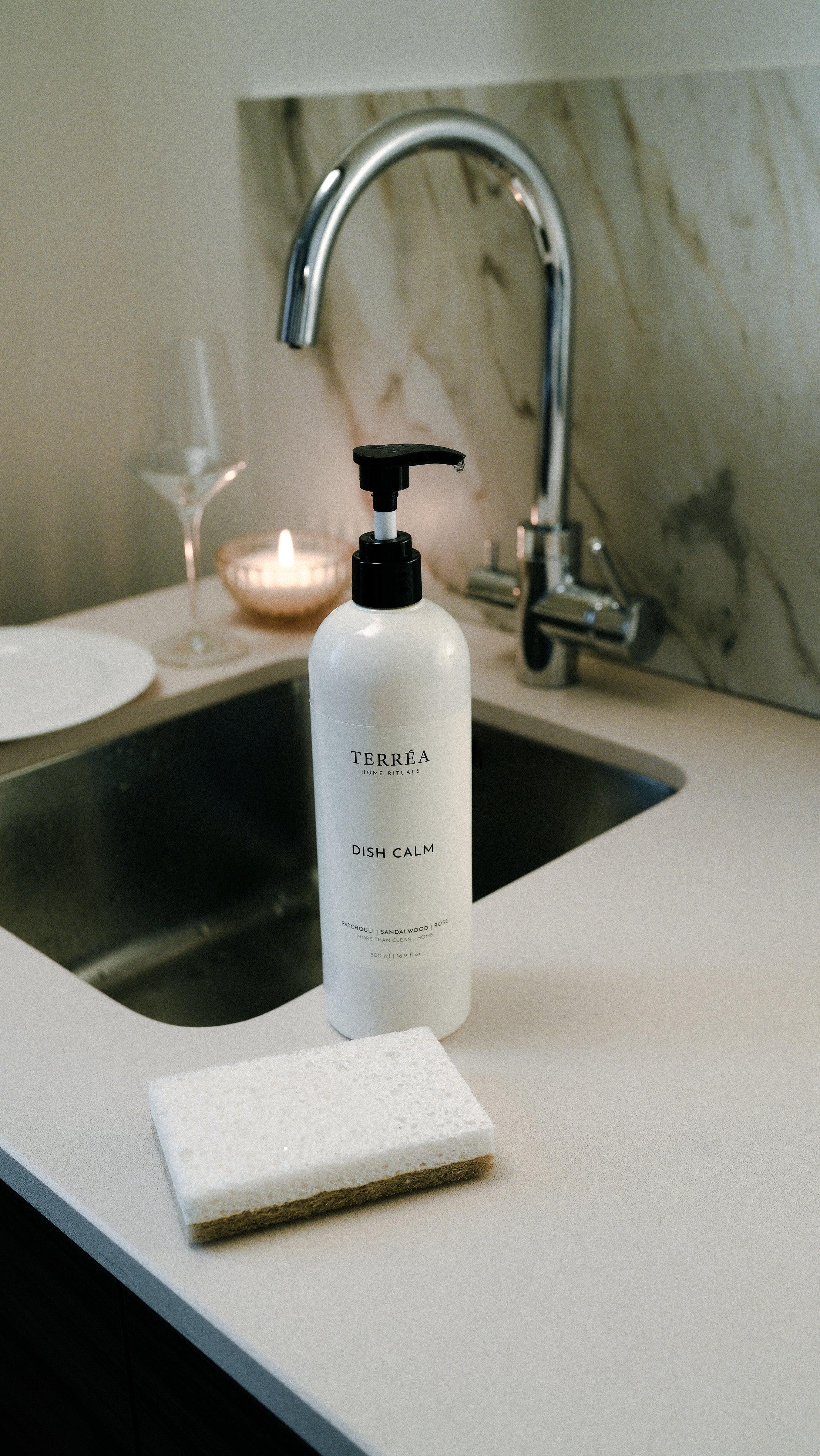 Eco-friendly dish soap with calming scent beside kitchen sink and sponge