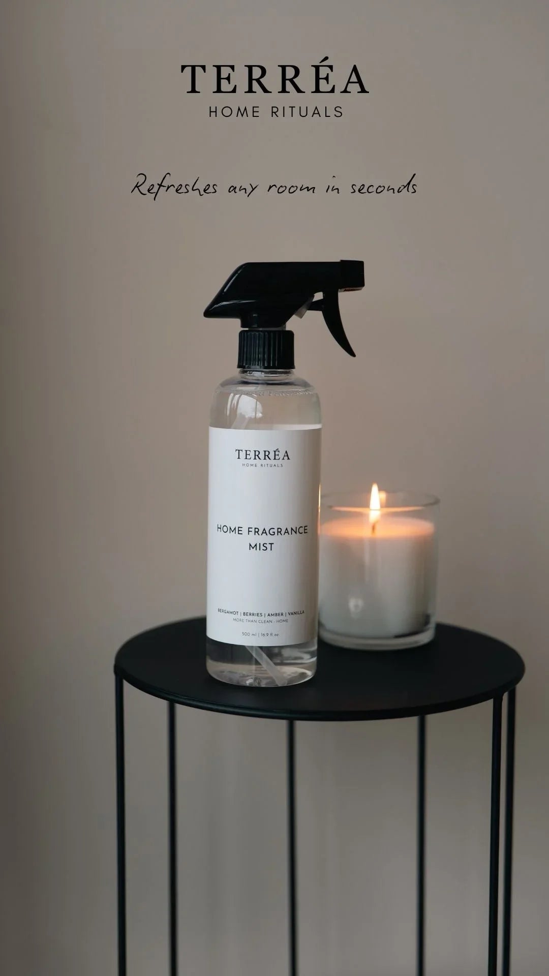 Home fragrance mist spray bottle with lit candle on black table, refreshing room scent