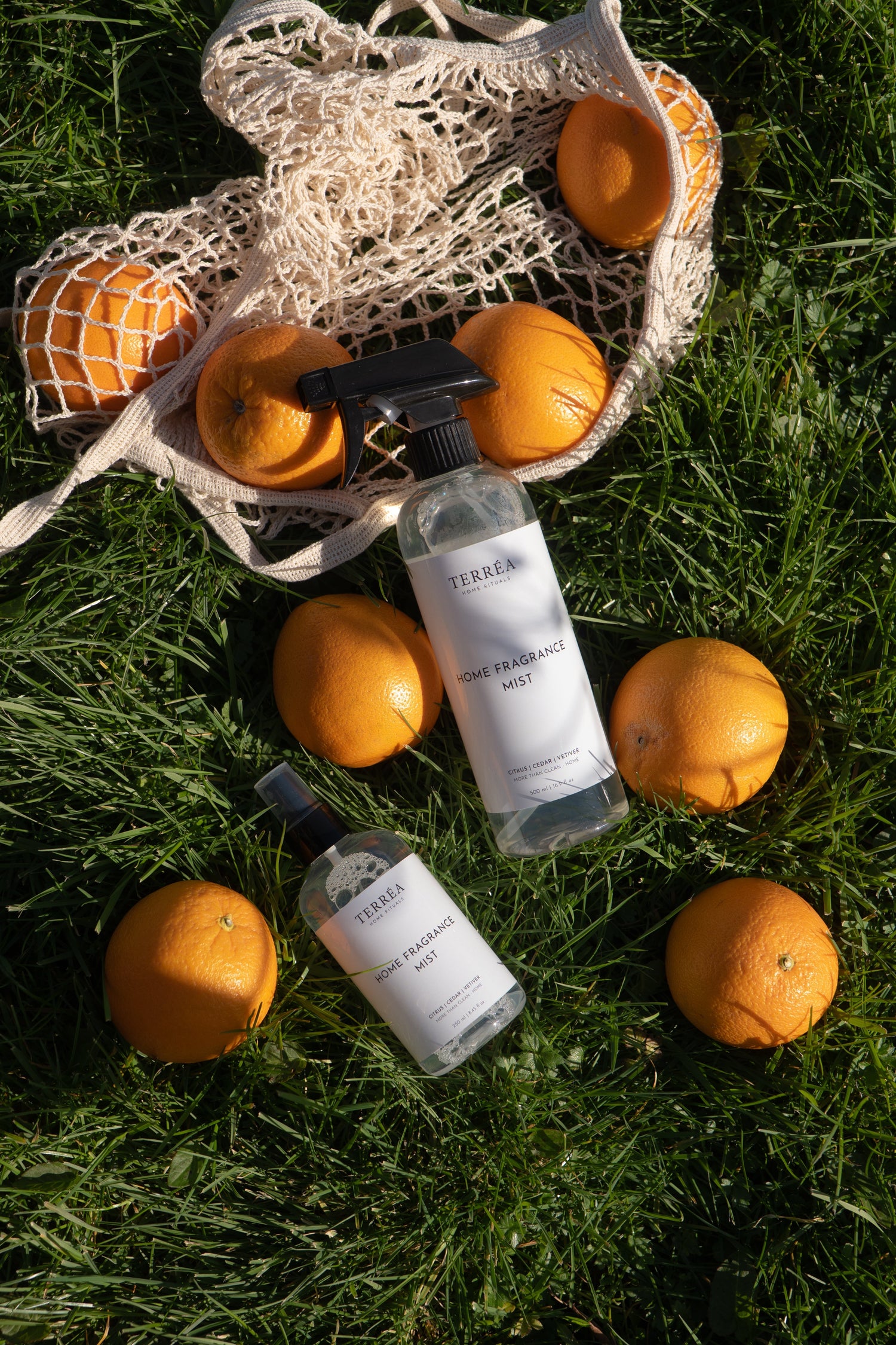 Citrus-scented home fragrance mist bottles with oranges on grass, eco-friendly luxury home care