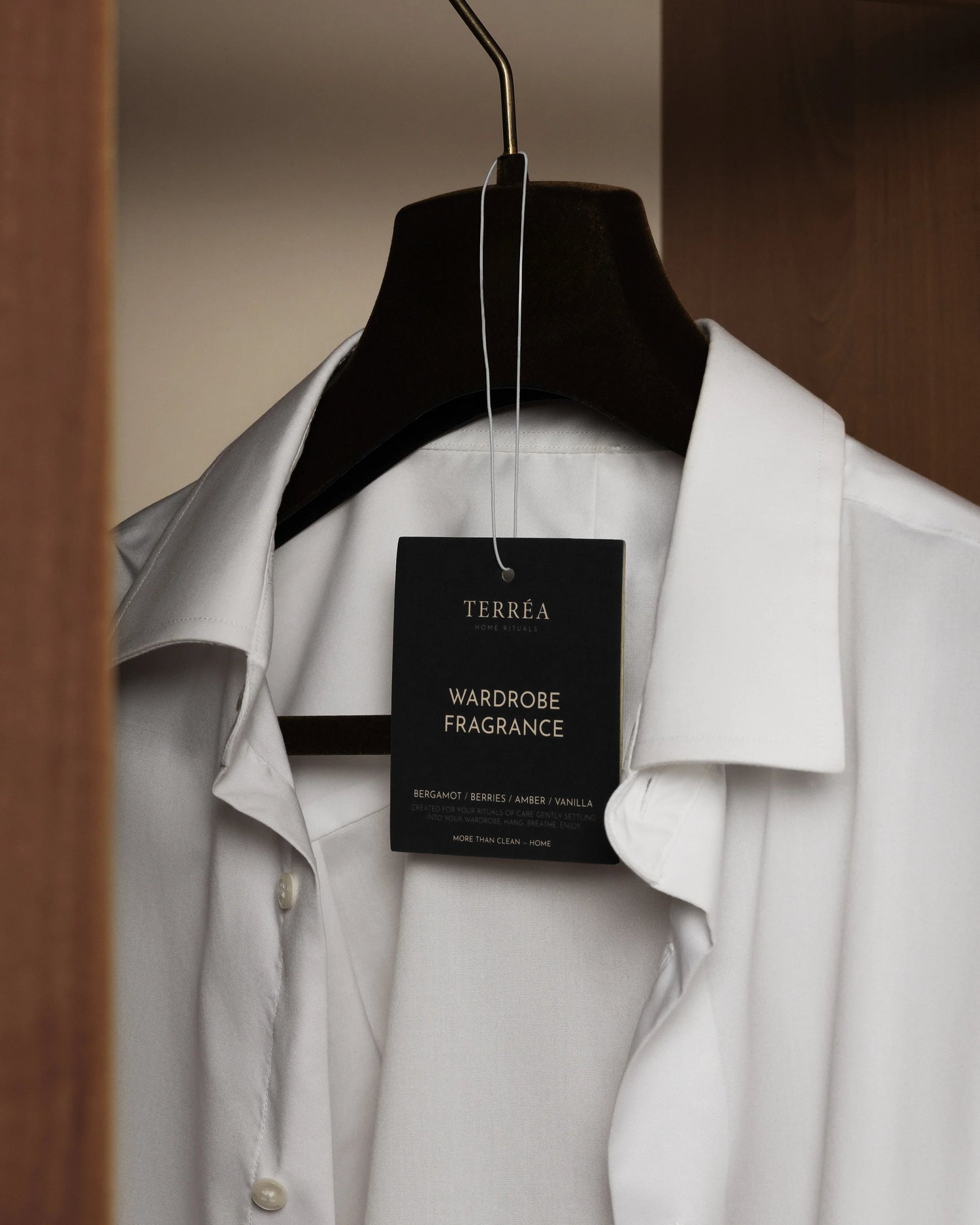 Wardrobe interior with a white shirt on a hanger and a Terréa Wardrobe Fragrance attached.