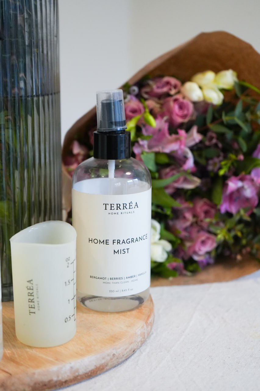 Terréa Home Fragrance Mist spray bottle on wooden tray with measuring cup and bouquet in background