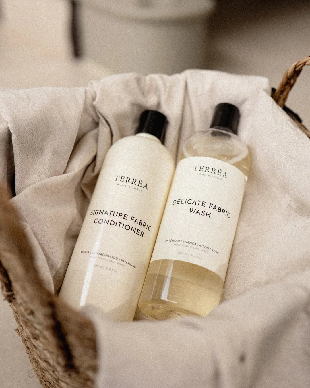 Terréa Signature Fabric Conditioner and Delicate Fabric Wash in a linen-lined wicker basket.