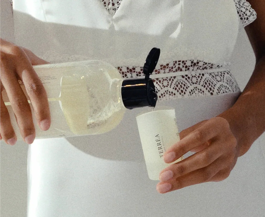 Woman pouring laundry detergent into a measuring cup in a nightdress, morning
