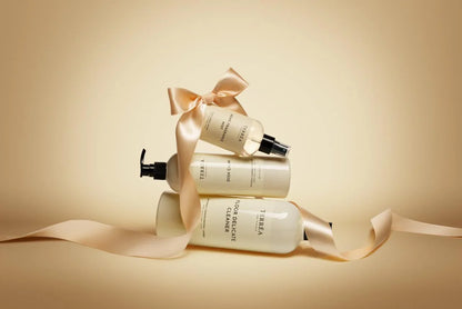 Three skincare bottles with ribbons on a beige background