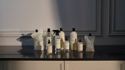 A full Terréa product collection arranged on a dark reflective kitchen counter, including refill pouches, fabric care, surface cleaner, floor cleaner, Dish Calm and Home Fragrance Mists, lit by warm evening sunlight against elegant wall panelling.