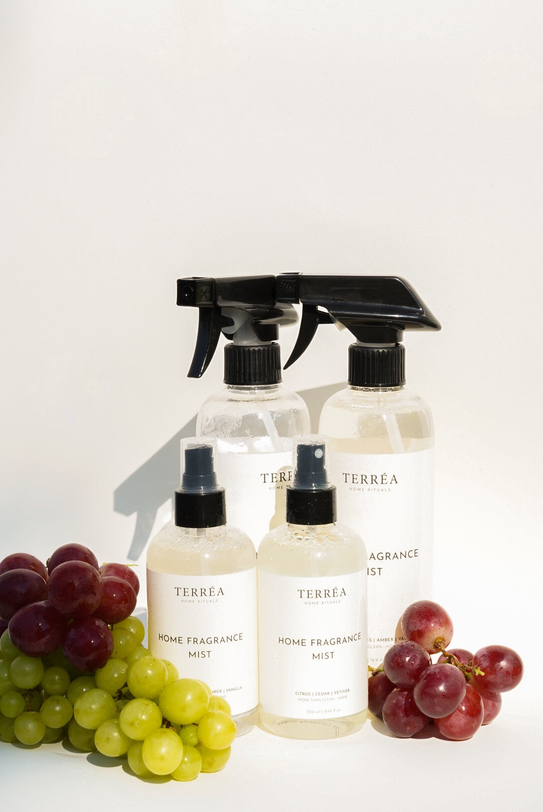 Terréa Home Fragrance Mist bottles styled with green and red grapes in bright natural light, highlighting the brand’s two fragrance moods.