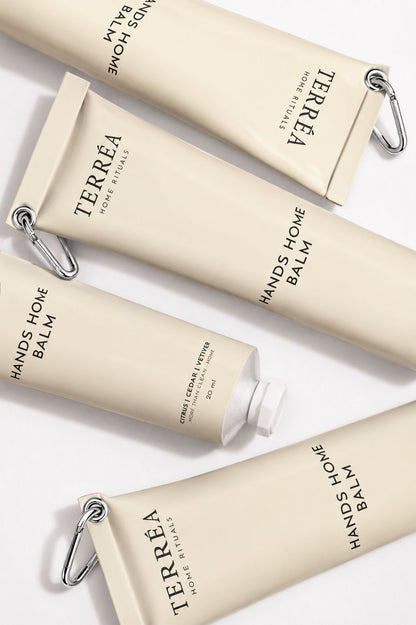 Terréa Hands Home Balm tubes arranged diagonally on a clean white surface with silver carabiner details.