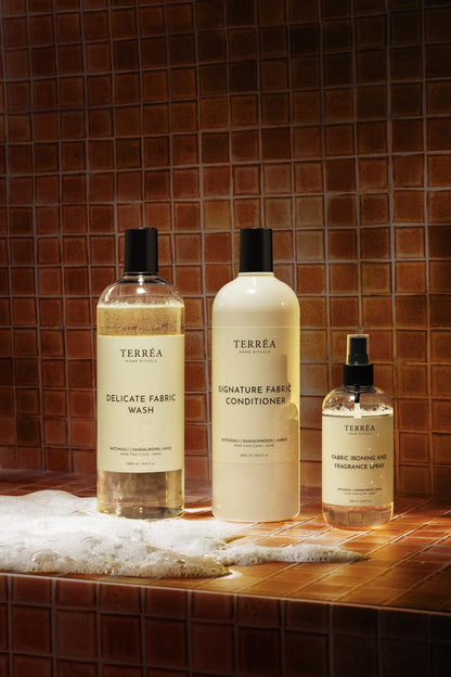 Three bottles of Terrea fabric care products on a tiled surface with a brown tile background.