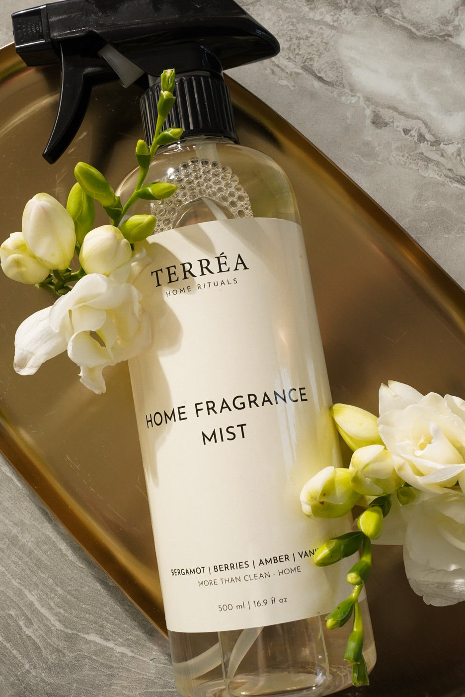 Terréa Home Fragrance Mist 500 ml close-up styled with white freesia and warm marble tones.