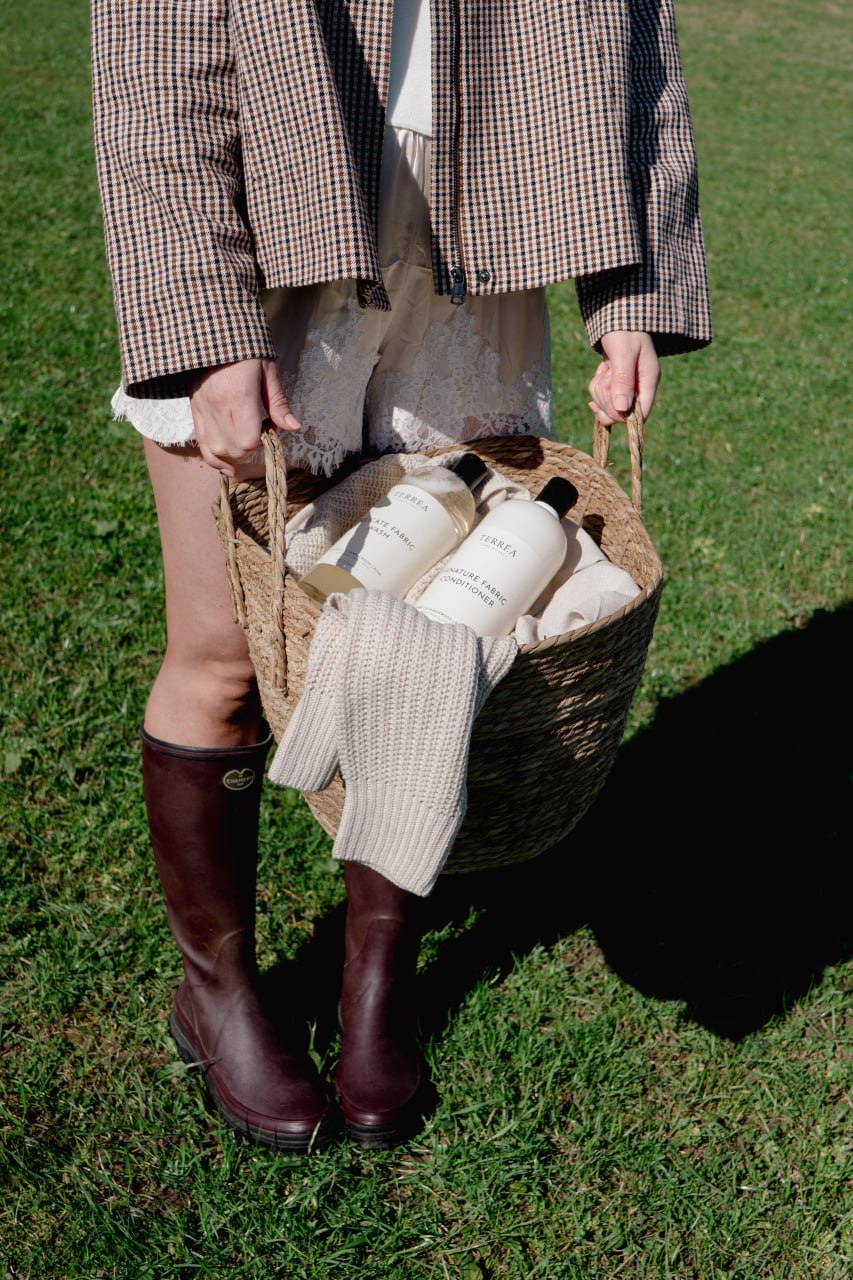 Wicker basket with Terréa Delicate Fabric Wash and Signature Fabric Conditioner, carried outdoors on a lawn.