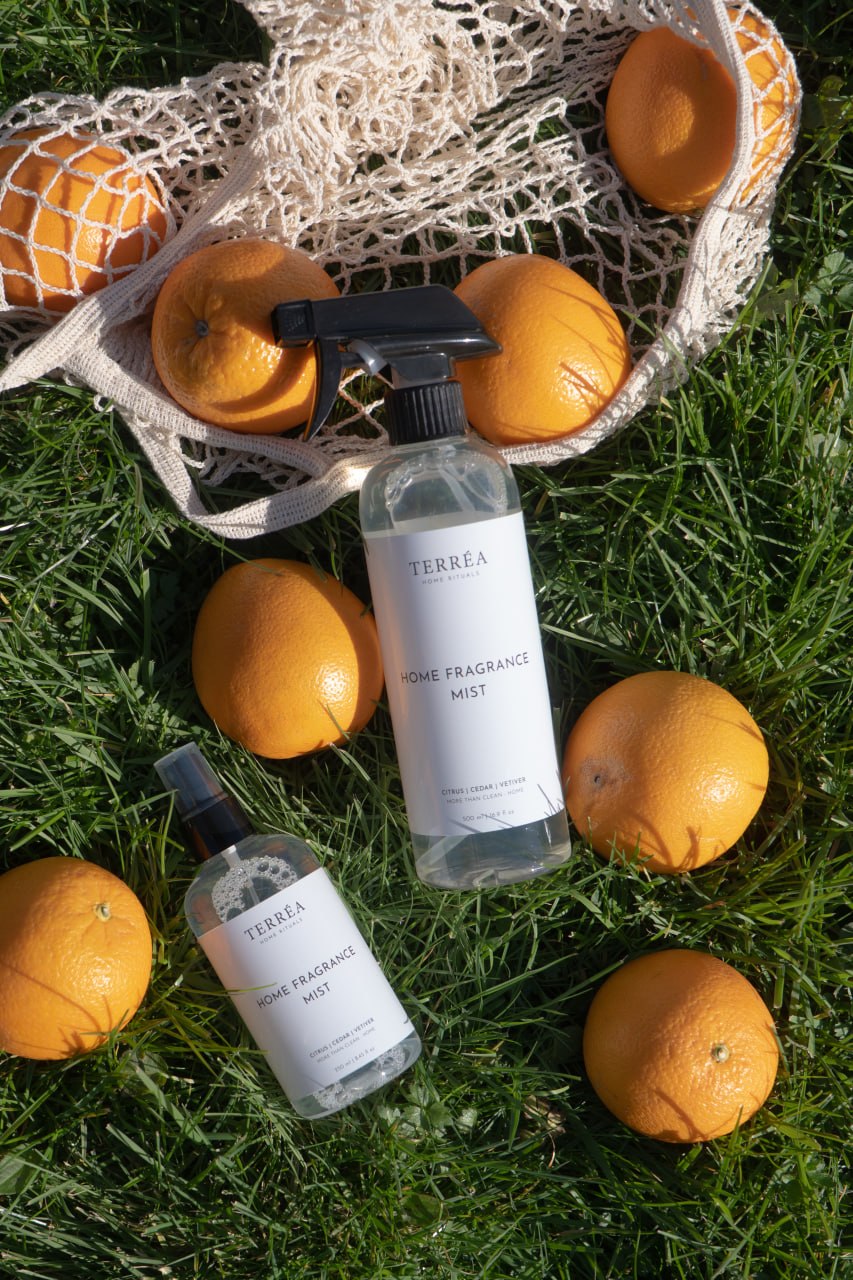 Terréa Home Fragrance Mist Citrus / Cedar / Vetiver bottles styled on grass among fresh oranges