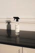 Spray bottle on a black countertop with a neutral background