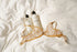 Two bottles of best laundry detergents products on a white textured surface with a gold bra.