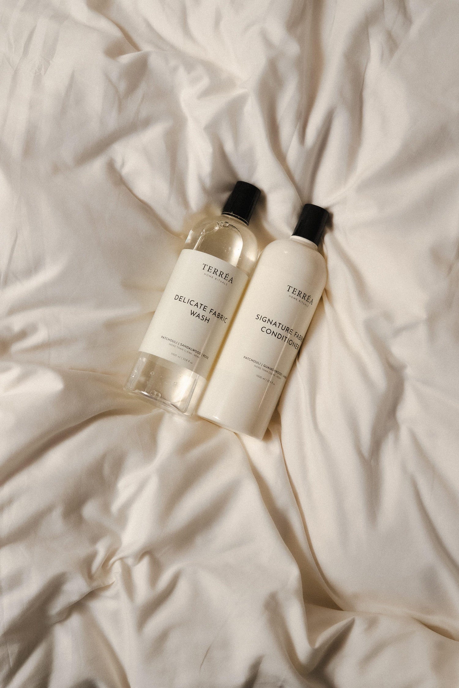 Two bottles of best laundry detergents and conditioner on a textured beige surface