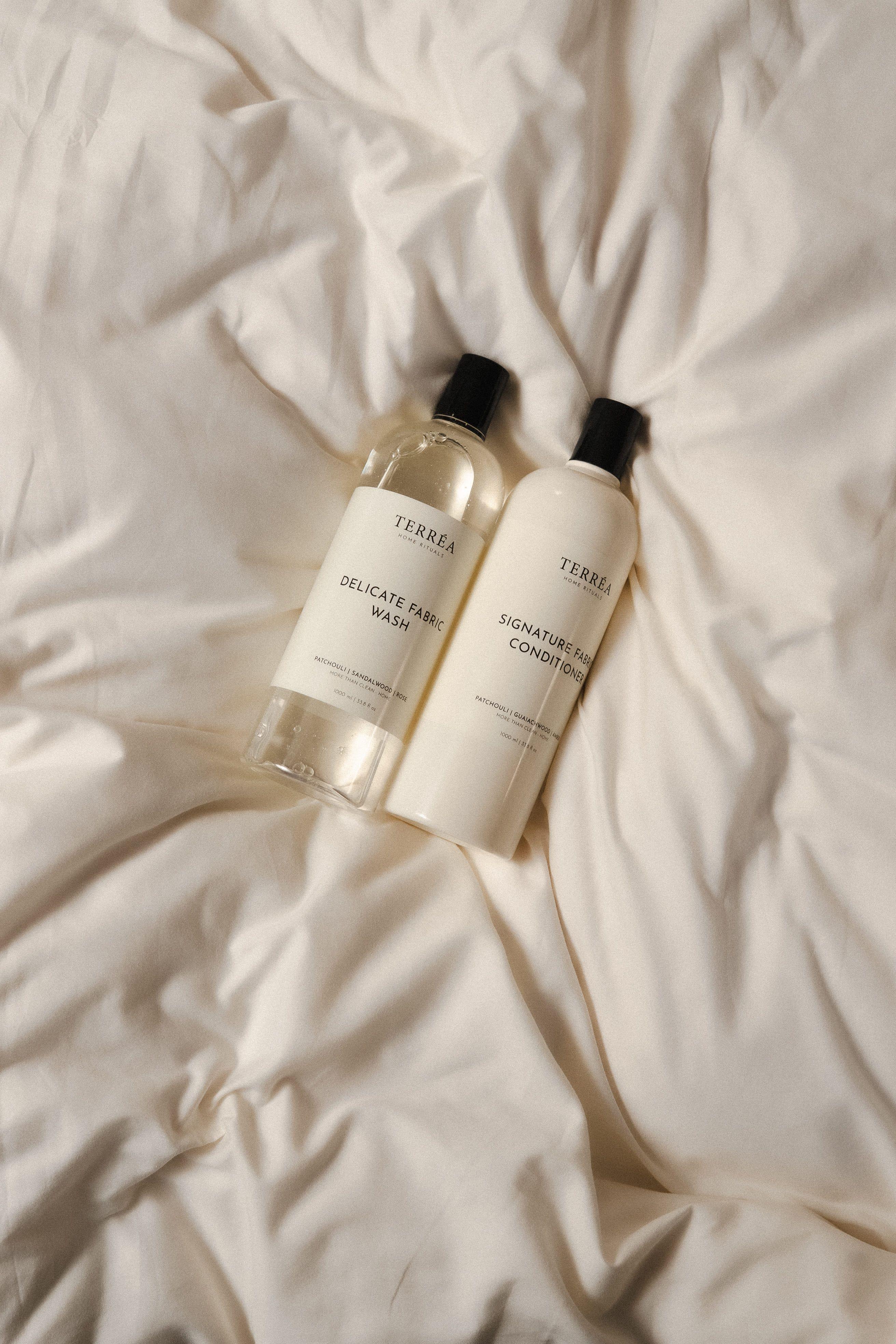 Two bottles of best laundry detergents and conditioner on a textured beige surface