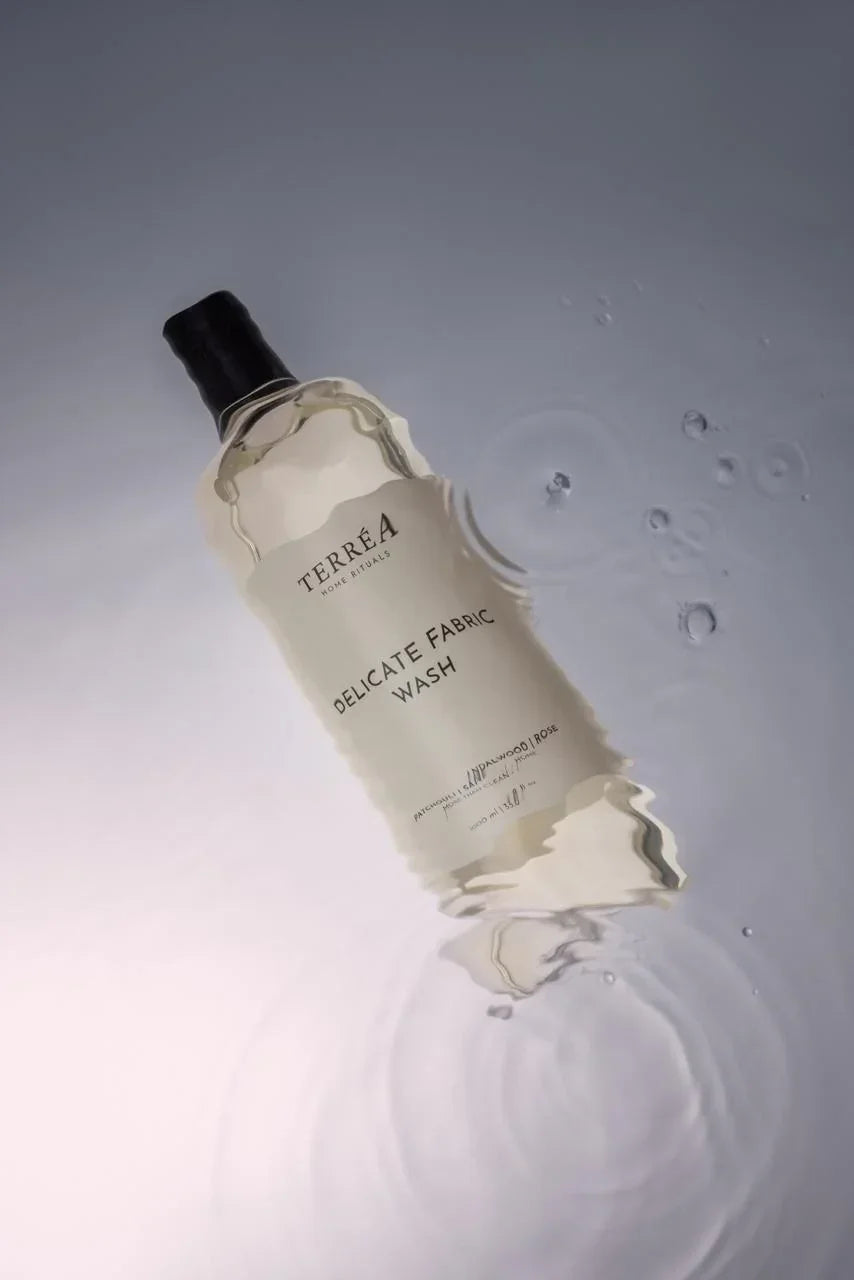 Bottle of Terrea Delicate Fabric Wash on a gray background with water droplets.
