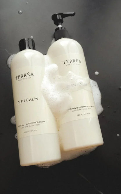 Two bottles of Terrea products on a black surface with bubbles.