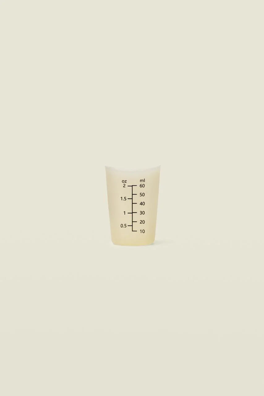 Small white measuring cup with black markings on a beige background