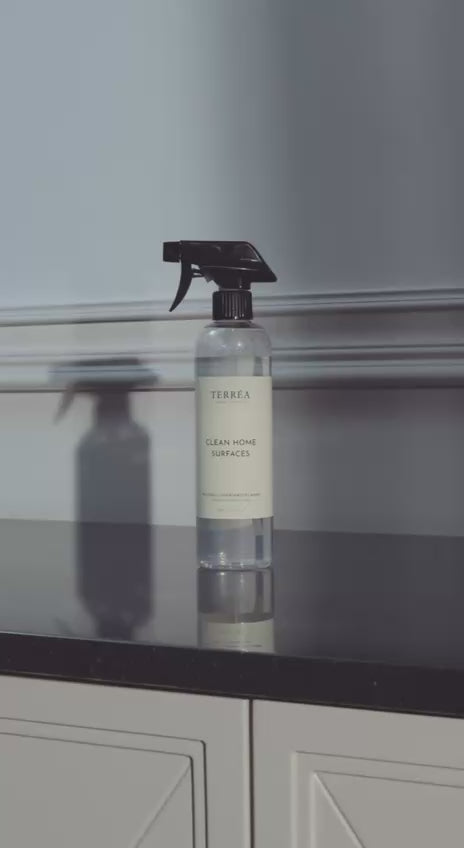 Terréa Clean Home Surfaces - woman wipes a marble countertop, mirror and table; calm, deep-clean home ritual.