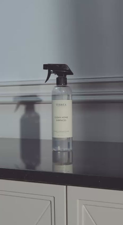Terréa Clean Home Surfaces - woman wipes a marble countertop, mirror and table; calm, deep-clean home ritual.