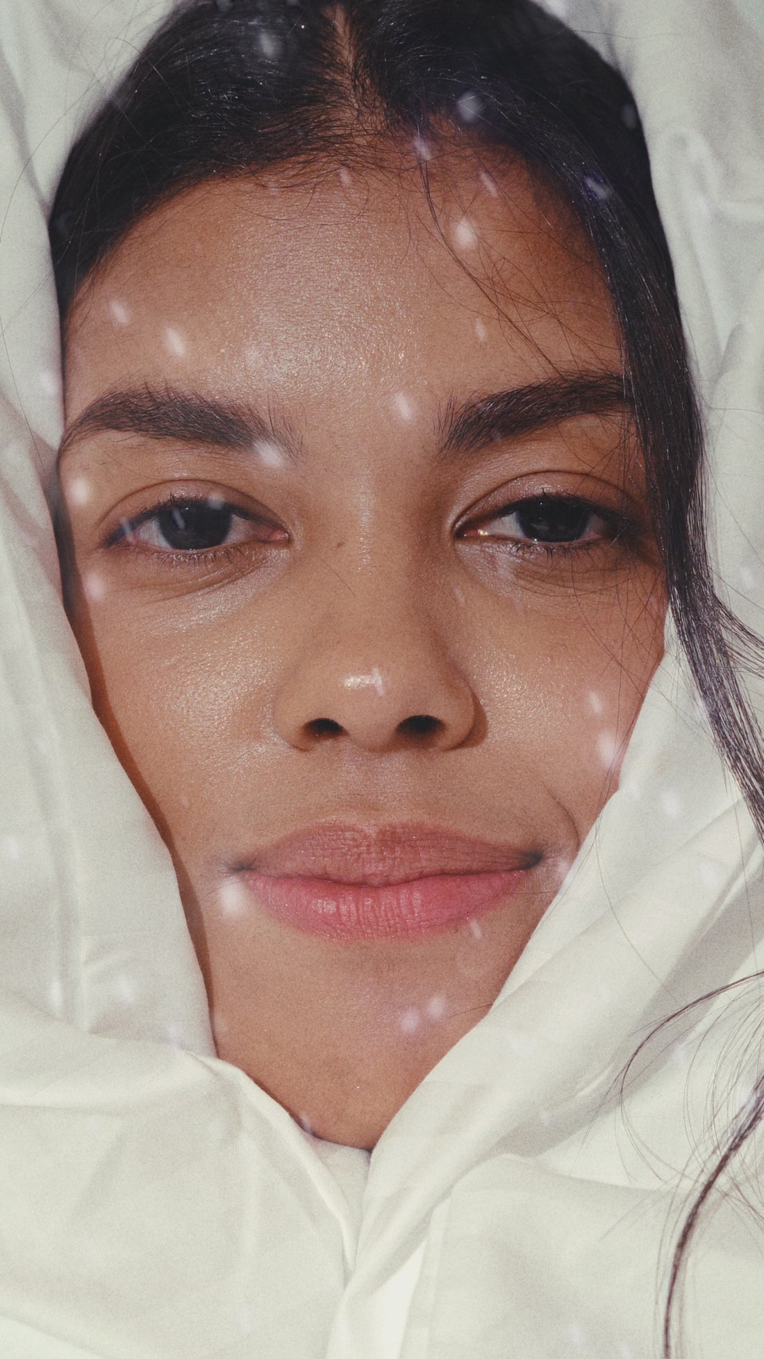 Cosy portrait of a Black woman wrapped in a soft blanket - calm, minimal aesthetic.