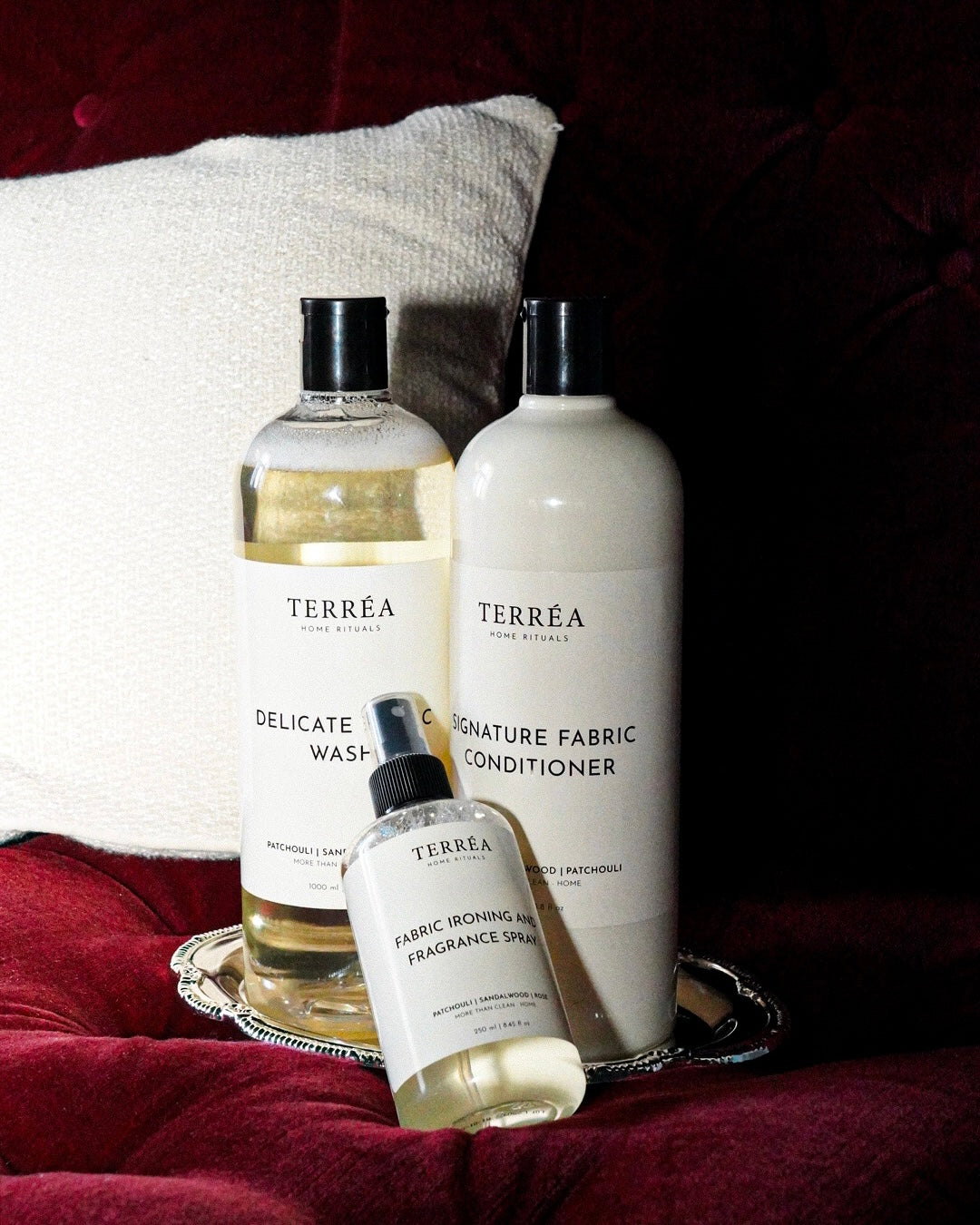 Terréa Delicate Fabric Wash, Signature Fabric Conditioner and Scented Ironing Water on a silver tray, red velvet sofa